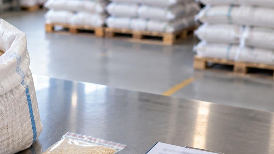 Stacked export sacks with stencilled lot codes and a heat-sealed plastic liner visible inside an open sack